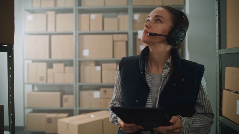 Radnica u skladištu sa slušalicama i tabletom proverava pakete
