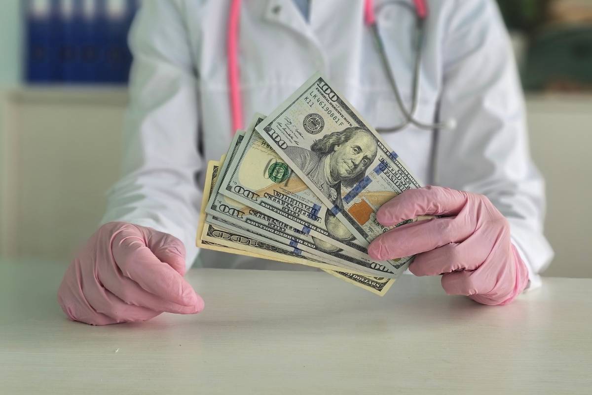 prikaz doktora sa rukavicama na rukama i novcem u ruci